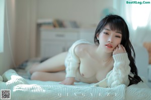 A woman sitting on a chair wearing a white fur coat.