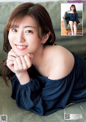 A woman in a blue dress sitting on a brown couch.