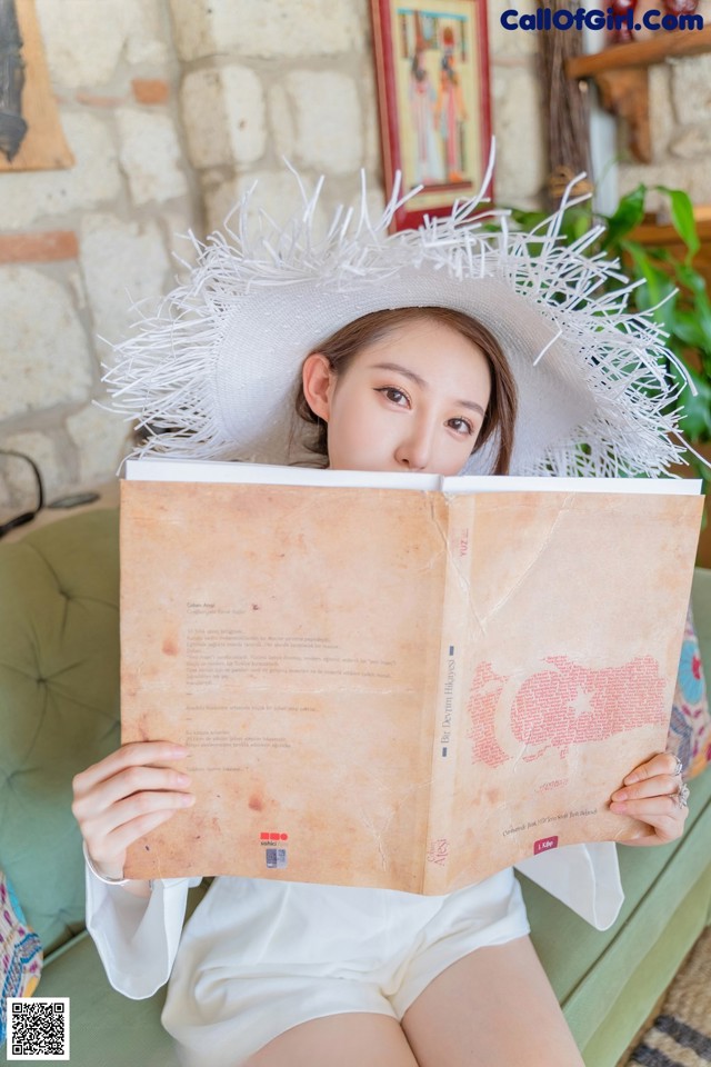 A woman in a white hat is reading a book.