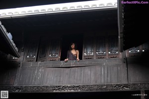 A naked woman sitting on the ground next to a fountain.