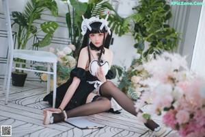 A woman in a maid outfit sitting on a chair.