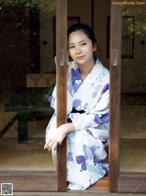 A woman in a kimono standing in front of a house.