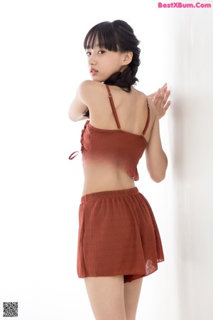 A young woman leaning against a wall with her hands on the wall.