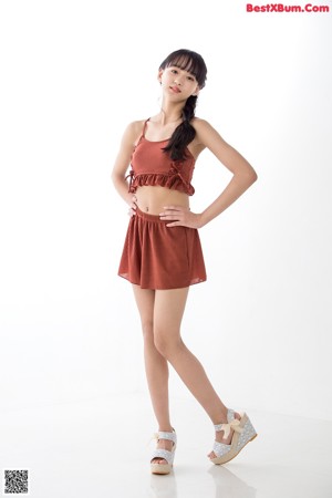 A woman in a brown top and shorts posing for a picture.