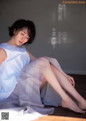 A woman sitting on a window sill next to a window.