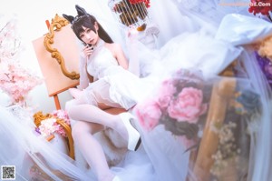 A woman in a white dress and cat ears posing for a picture.