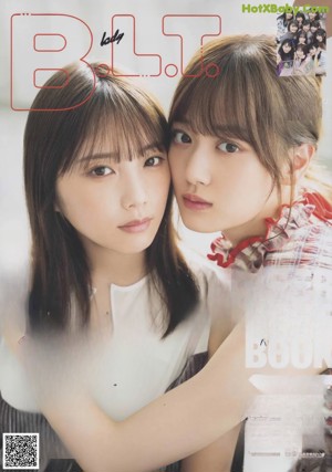 Two young women standing next to each other on a sidewalk.