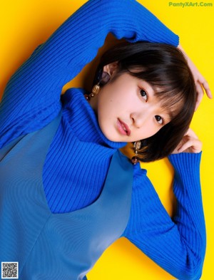 A woman in a blue sweater and blue pants posing for a picture.