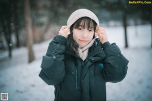 A woman wearing a black jacket and a scarf in the snow.