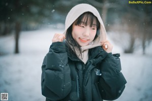 A woman wearing a face mask standing in the snow.