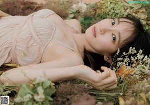 A pregnant woman laying in a field of flowers.