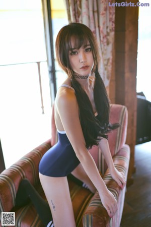 A woman in a black bathing suit sitting on a bed.