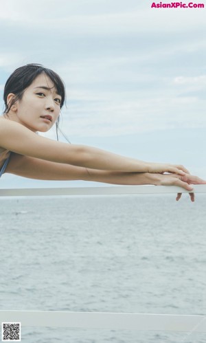 A woman in a blue tank top is making a peace sign.