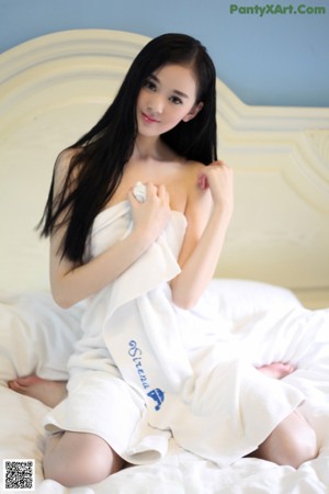 A woman in a white towel standing in a bathroom.