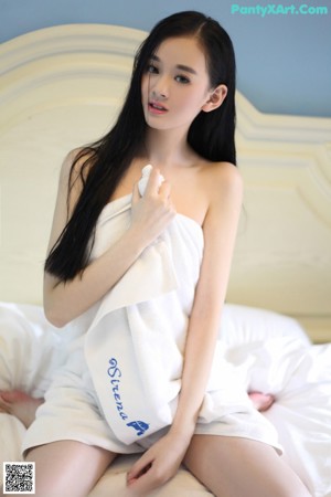 A woman wrapped in a white towel in a bathroom.