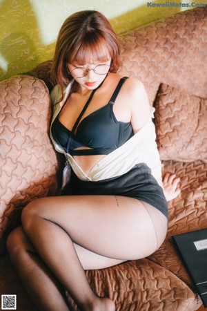 A woman in a black lingerie sitting on a wooden floor.
