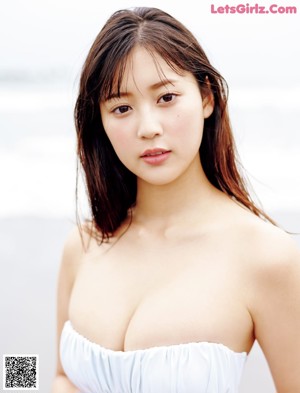 A woman in a white top and black skirt leaning against a wall.