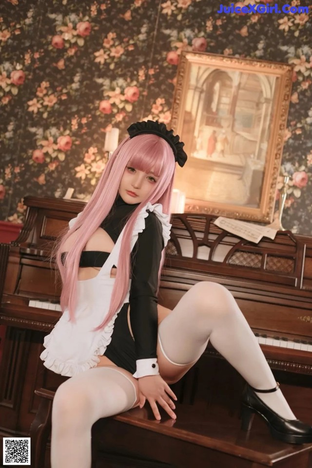 A woman with pink hair sitting on a piano.