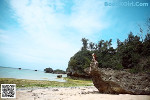 A woman sitting on a rock with her legs crossed.
