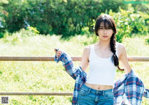 A young woman sitting on a bench in a field.