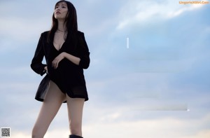 A woman standing on a balcony next to the ocean.