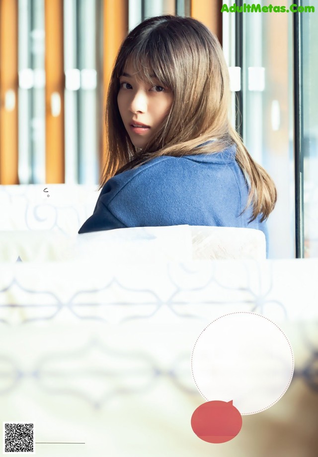 A woman with long hair standing in front of a window.