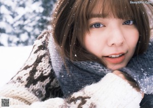 A woman standing in the snow wearing a scarf.