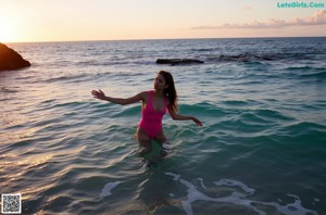 a woman in a pink and white bathing suit posing for the camera