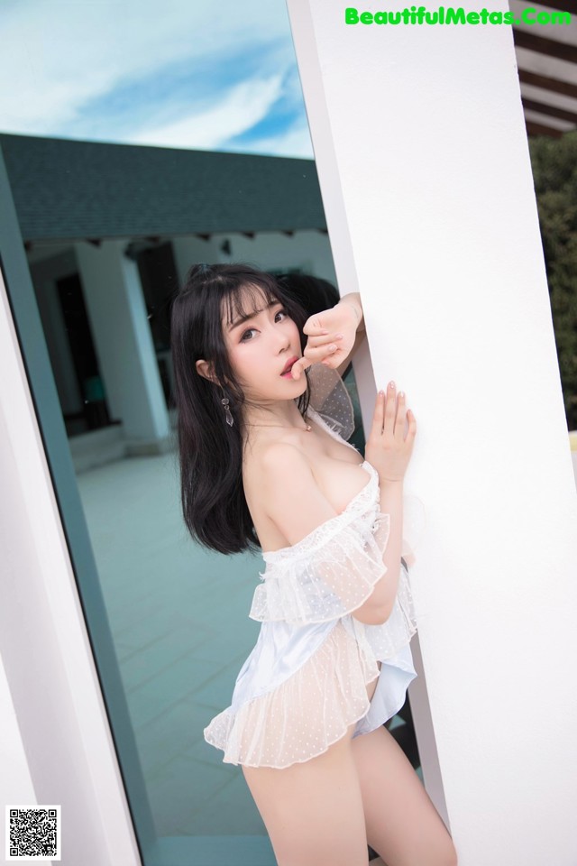 A woman in a white lingerie leaning against a wall.