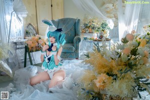 A woman in a bunny costume sitting on a blue couch.