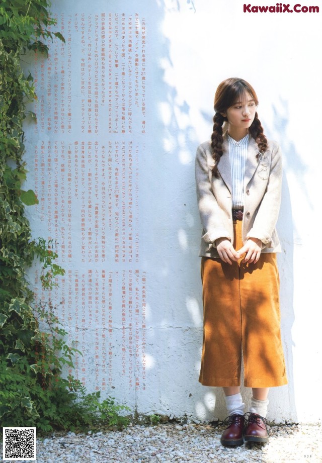 A woman standing in front of a white wall.