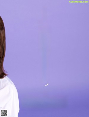 A woman in a white shirt dress posing for a picture.