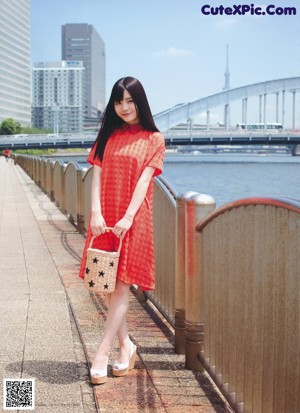 A woman with long black hair standing in front of a city.