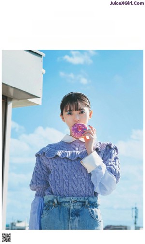 A woman in a blue sweater and denim skirt holding a lollipop.