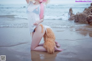 A woman in a bikini and a cat hat on the beach.