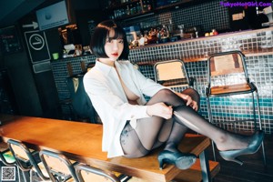 A woman in black stockings and a white shirt posing in a restaurant.