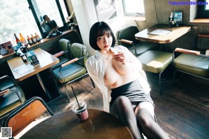 A woman in a white shirt and black stockings standing in front of a bar.