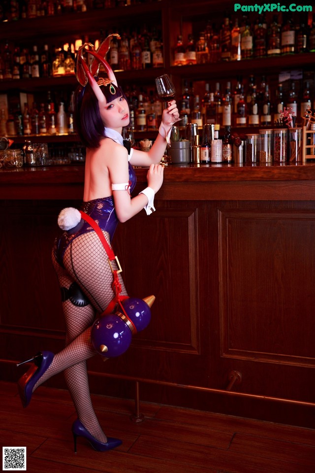 A woman dressed as a devil holding a glass of wine.