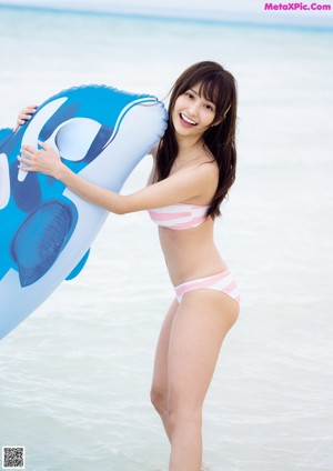 A woman in a pink bikini laying on a log on the beach.