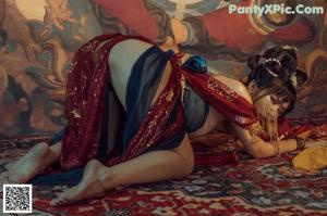 A woman in a red and gold outfit laying on a rug.